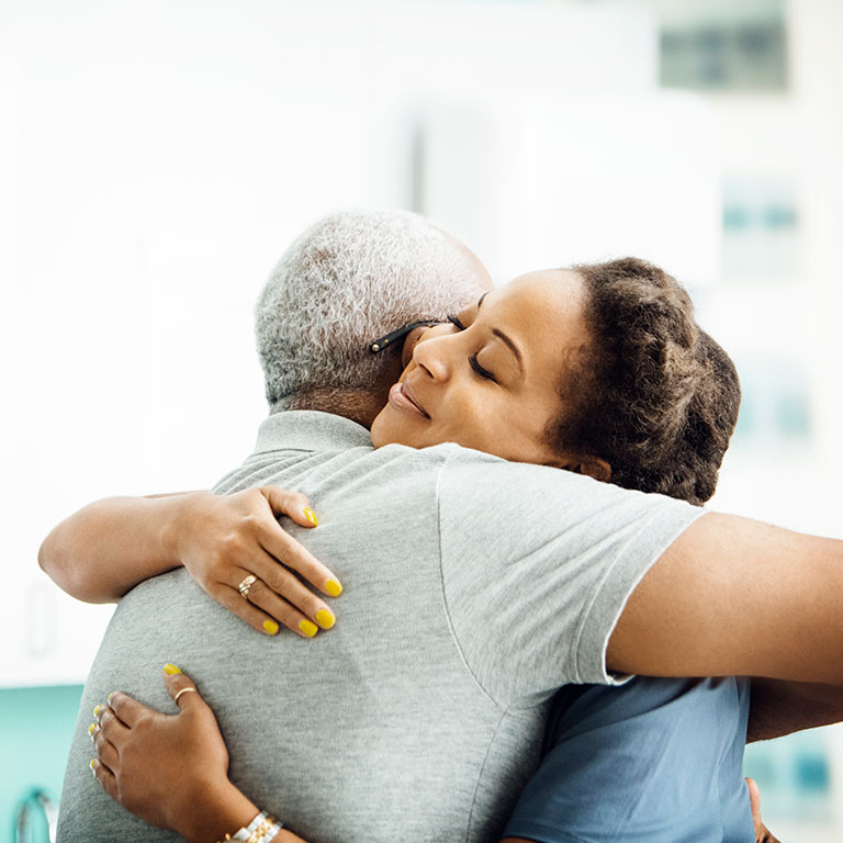 A senior man hugging caregiver in doctors office