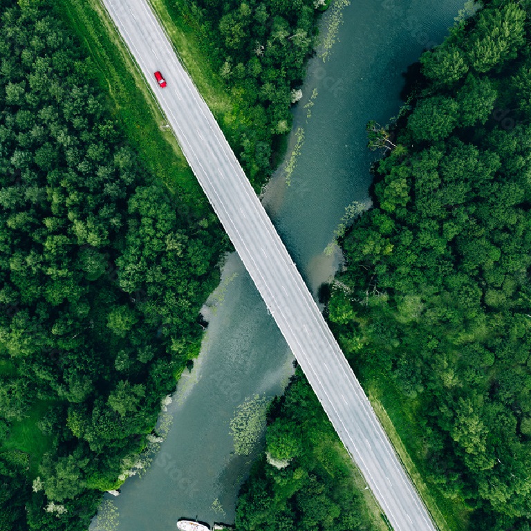 Aerial view of bridge road with car over blue river and green woods in Finland