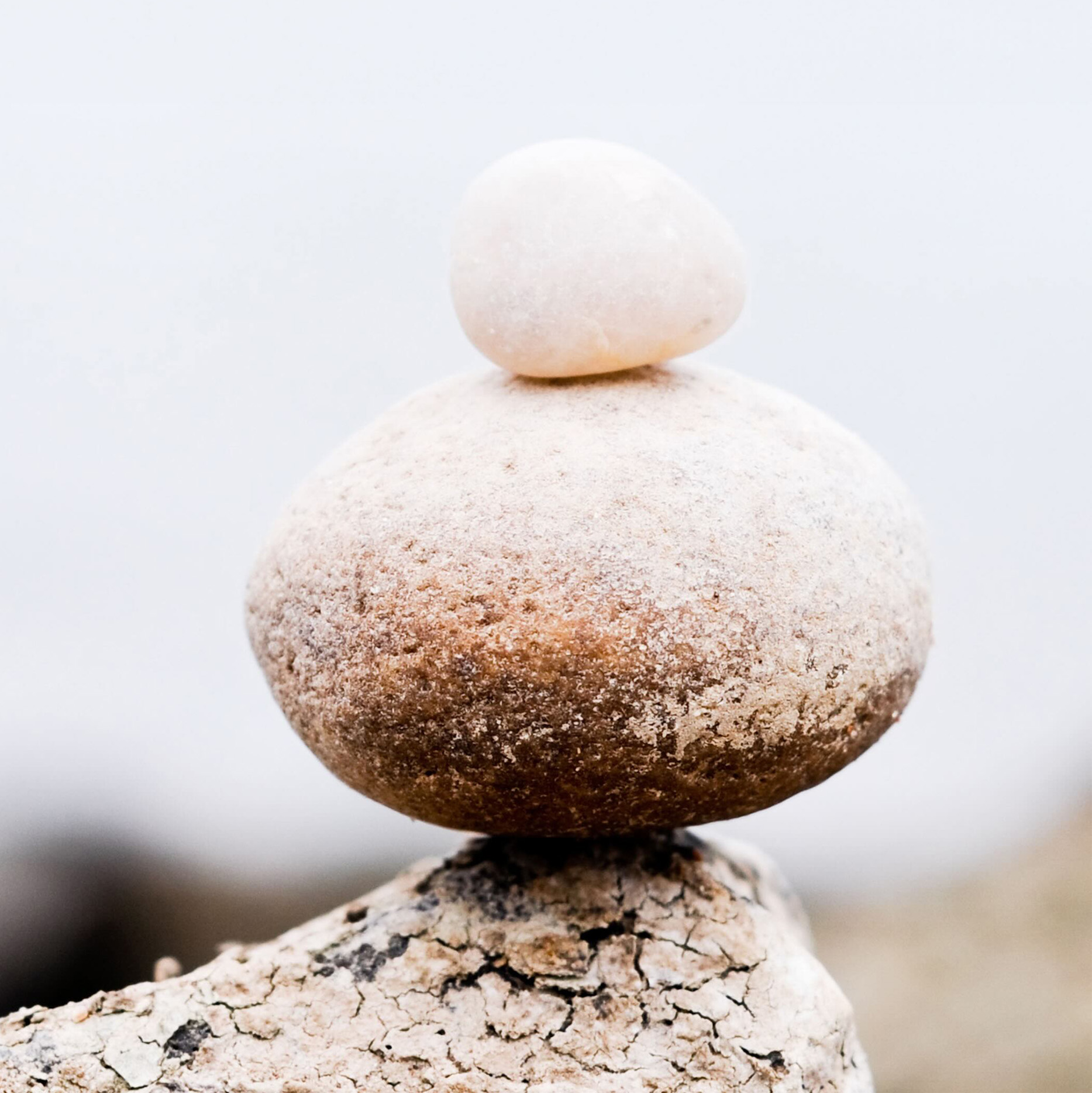 rocks on a beach, piled ontop of each other, grey aestehtic, 16:9, beach photo.