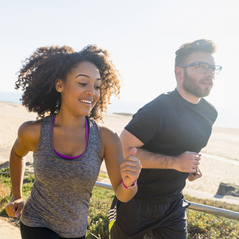 Couple running along pathway by beach