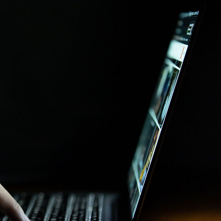 Hand of a man using laptop computer for hacking or steal data at night in office. Hacking concept