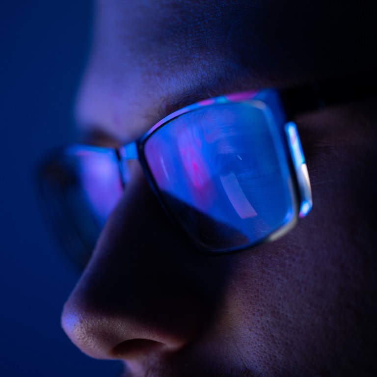 Close-up of a part of a male human face with glasses in neon light